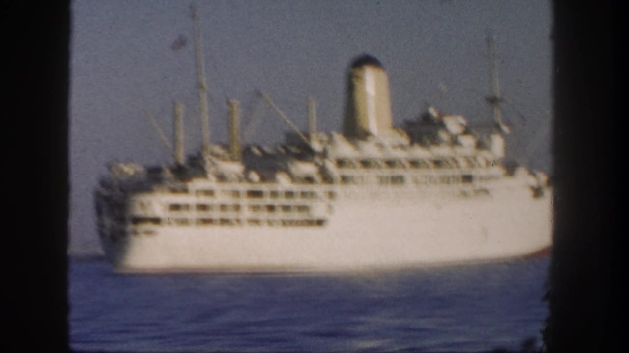 White passenger liner seen from a distance off San Diego, with stacked decks, a tall funnel, and calm Pacific water.