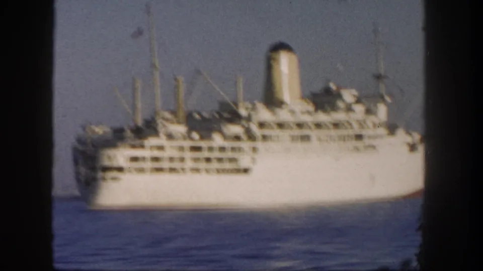 White passenger liner seen from a distance off San Diego, with stacked decks, a tall funnel, and calm Pacific water.