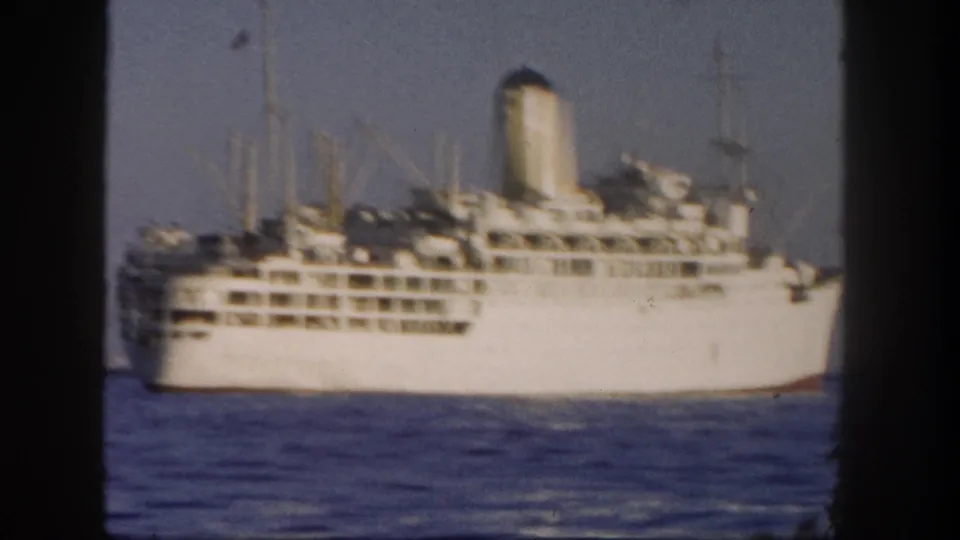 8mm frame of a large white ocean liner off San Diego, with several decks, a funnel, and soft handheld focus.