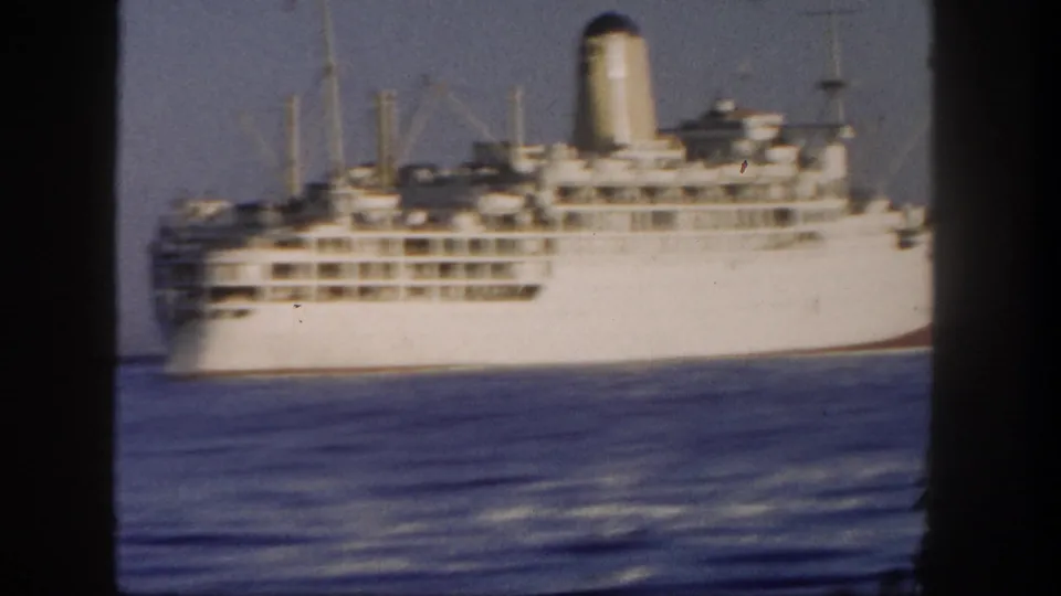 Final 1962 home-movie frame showing the white liner broadside on calm Pacific water, with deck rows and funnel visible.