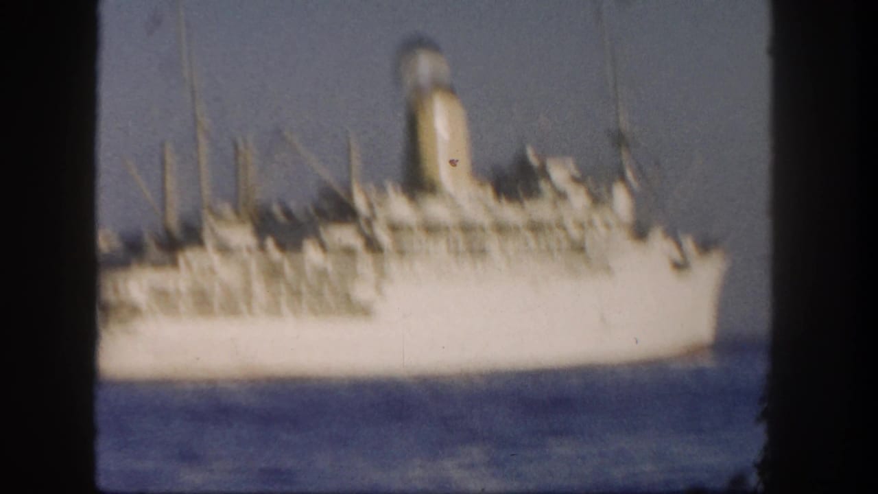 White passenger ship seen across blue water with dark film-frame borders.