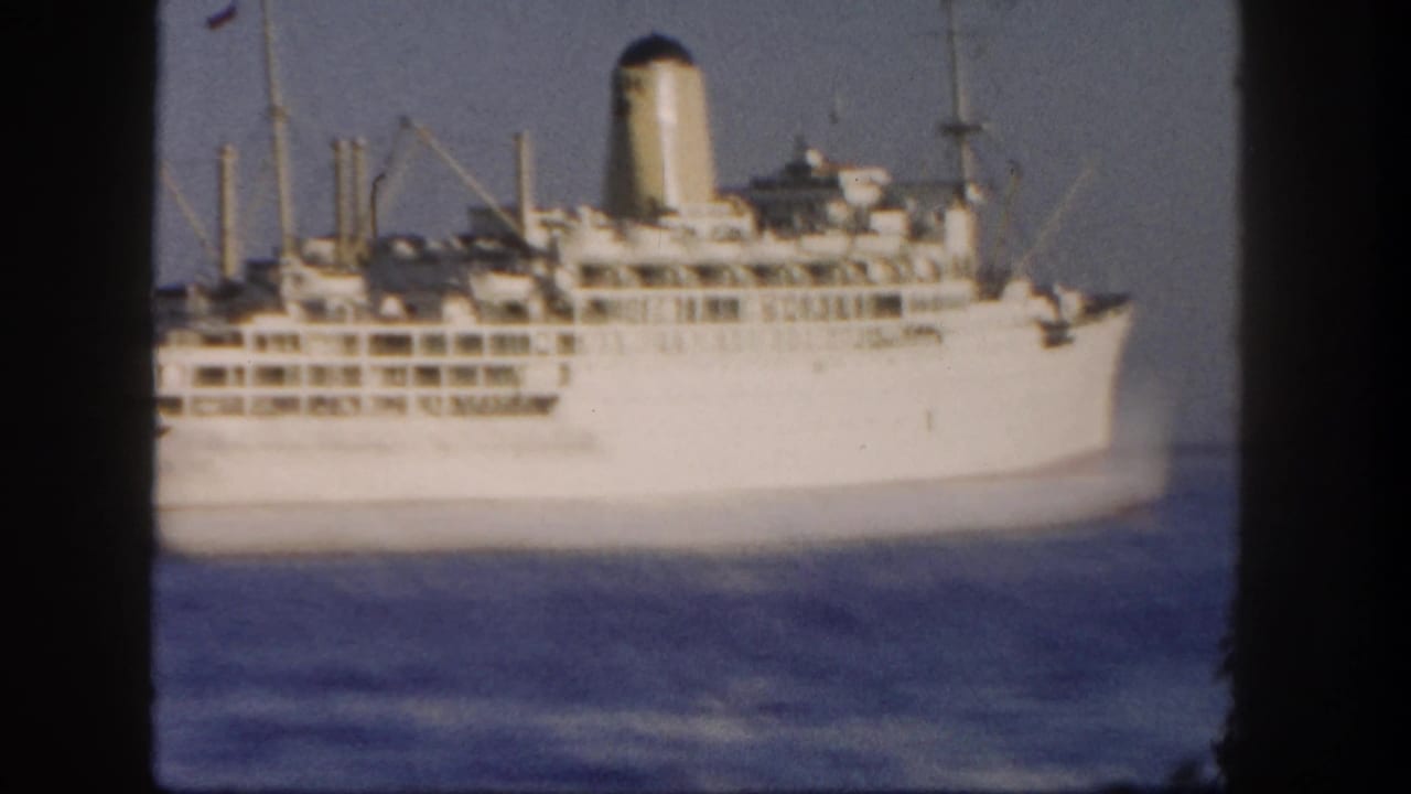 1962 San Diego 8mm frame with a large white passenger ship in profile on calm water, showing decks, funnel, and masts.