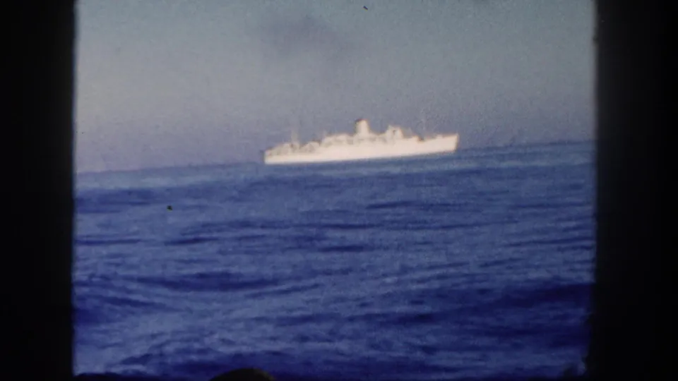 1962 San Diego 8mm frame showing a distant white passenger ship near the horizon, filmed over rippling blue water.