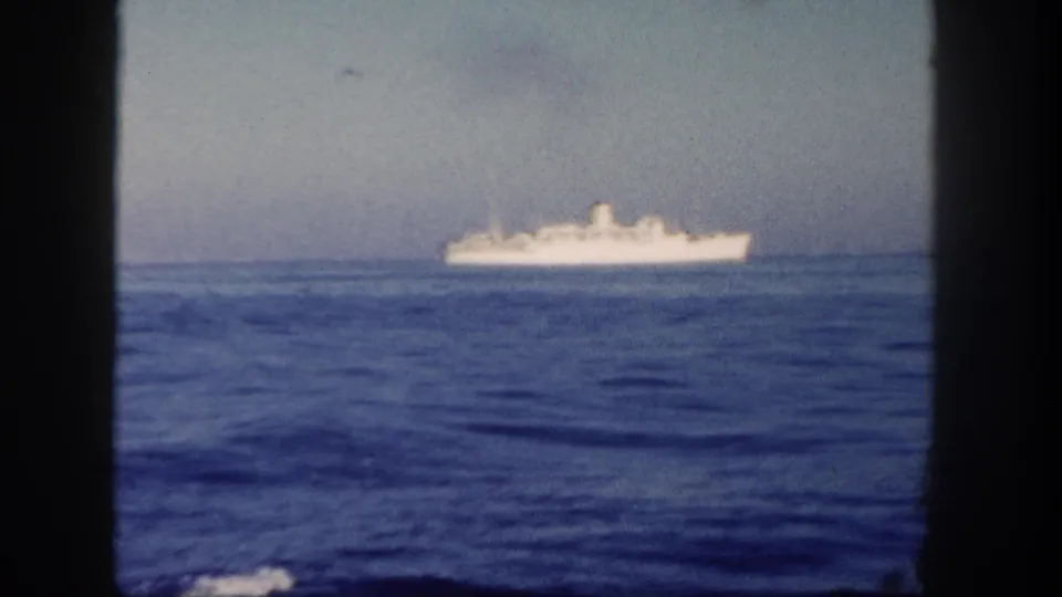 1962 San Diego 8mm frame with a small white passenger ship on the horizon and dark borders from the film or filming position.