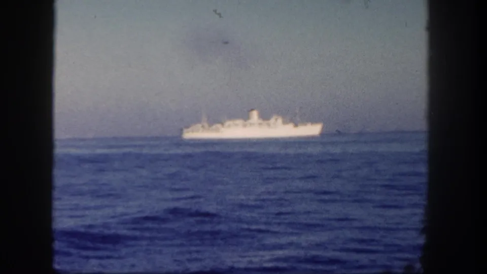 1962 8mm view near San Diego showing a distant white ship at sea through dark window framing.