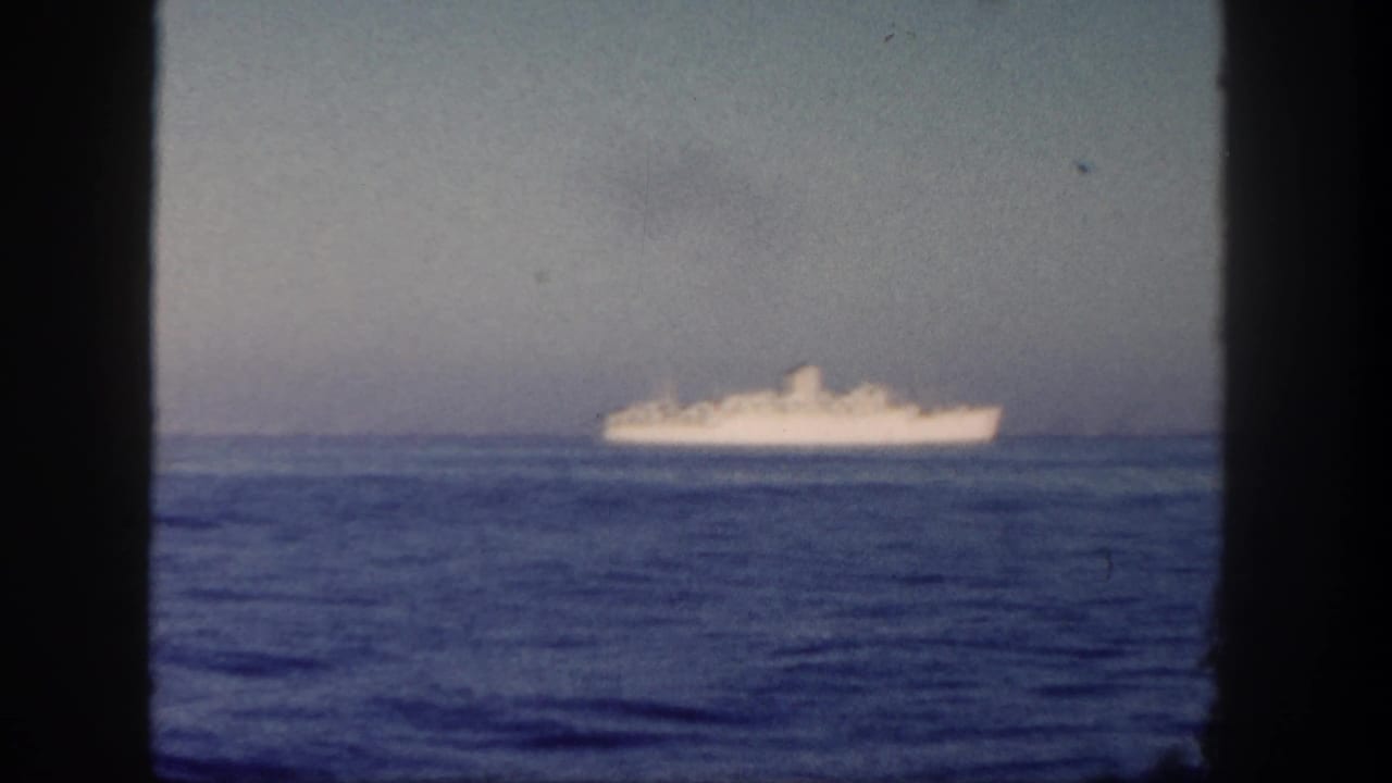 Distant white ship at sea in 1962 home-movie footage, viewed through a window frame near San Diego.