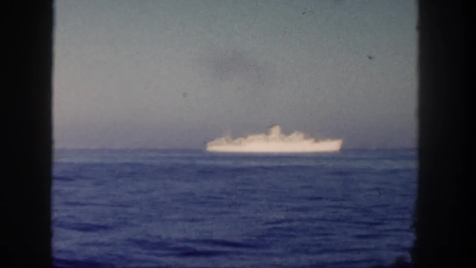 Distant white ship at sea in 1962 home-movie footage, viewed through a window frame near San Diego.