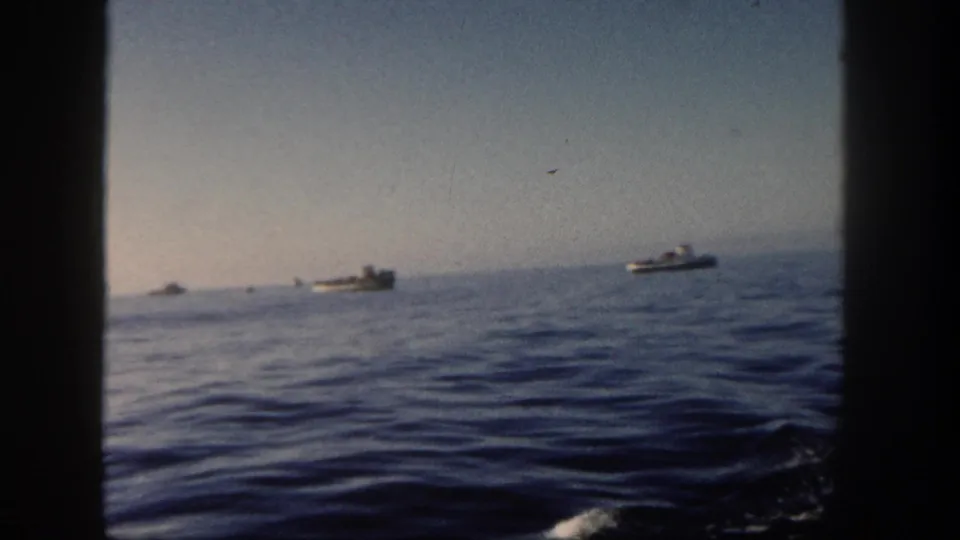San Diego 1962 8mm frame with small boats on the horizon, dark porthole-like edges, and rippled ocean water.
