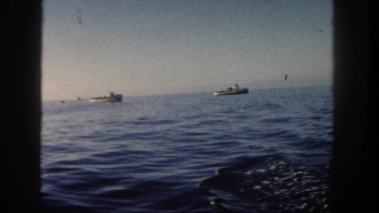 1962 San Diego home-movie frame showing calm ocean, distant small boats, pale sky, and visible 8mm frame borders.