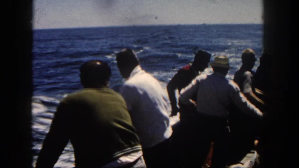 1962 San Diego boat-deck view with several passengers leaning or seated as wake trails across the open water.