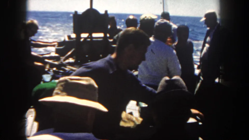 1962 San Diego 8mm footage shows men on a fishing boat deck, framed by dark edges, with blue water in the background.
