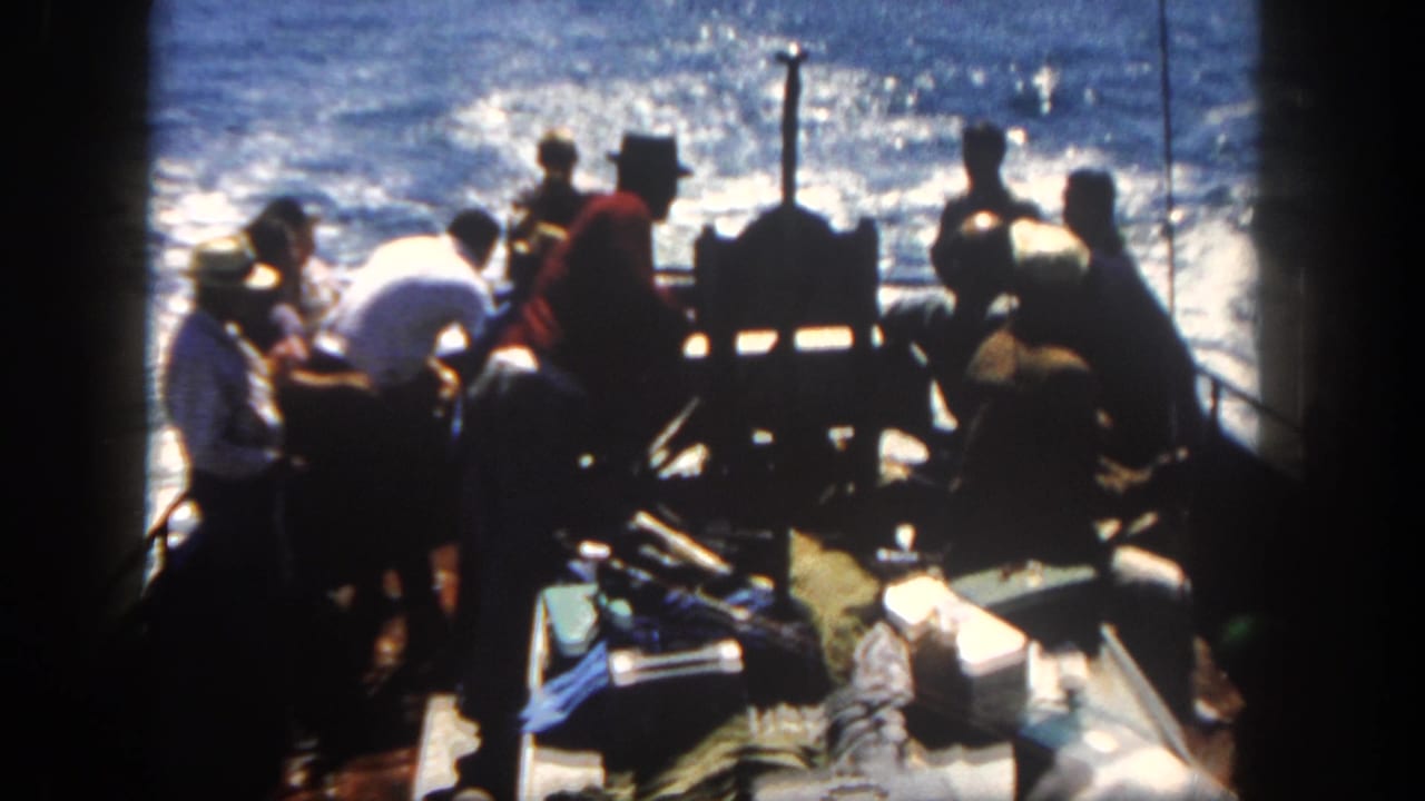 Group of men on a boat stern near equipment with choppy water in the background.