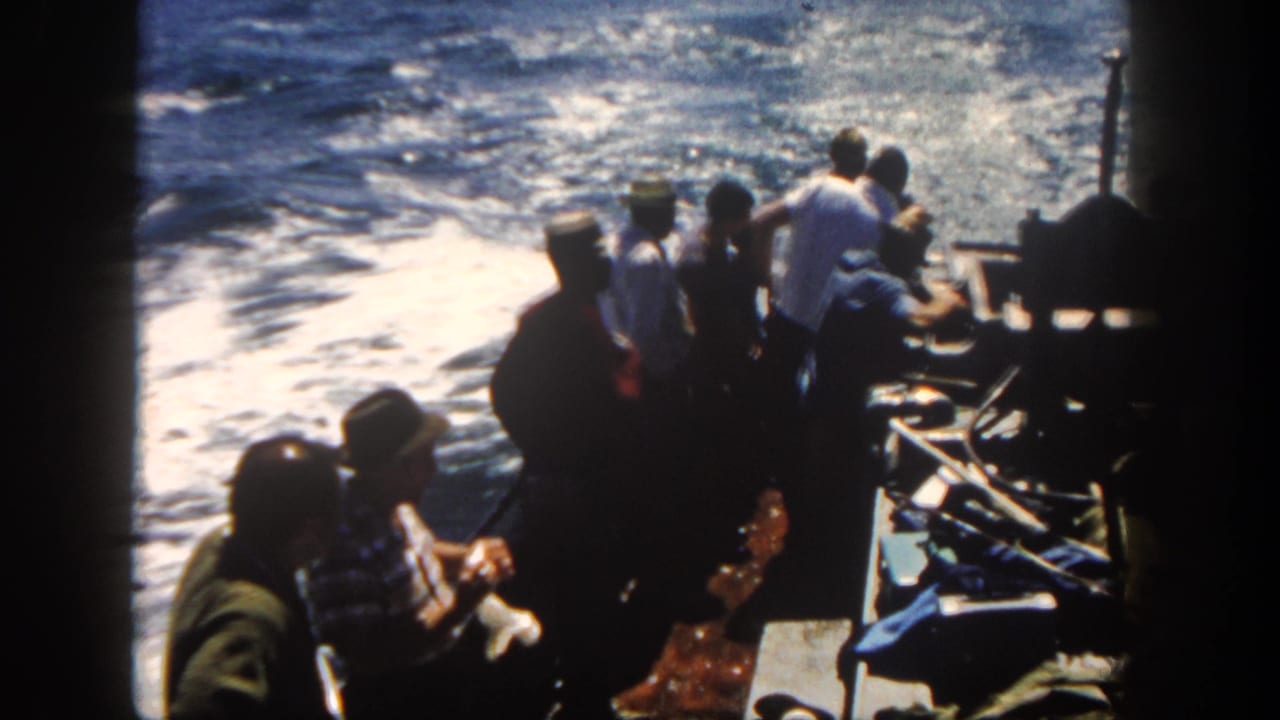 1962 San Diego boating scene with passengers silhouetted against sunlit, foamy water from an onboard 8mm view.