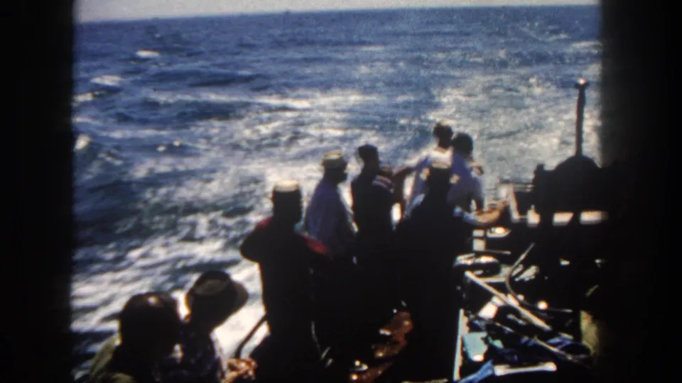 1962 San Diego home-movie frame showing silhouetted boat passengers against bright choppy coastal water.