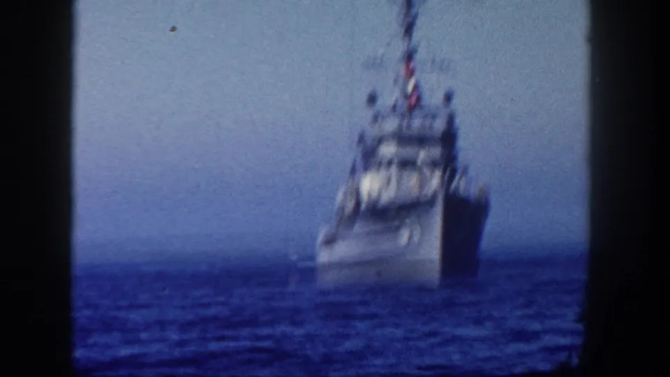1962 San Diego 8mm frame showing a distant Coast Guard vessel on open blue water, softened by handheld focus.