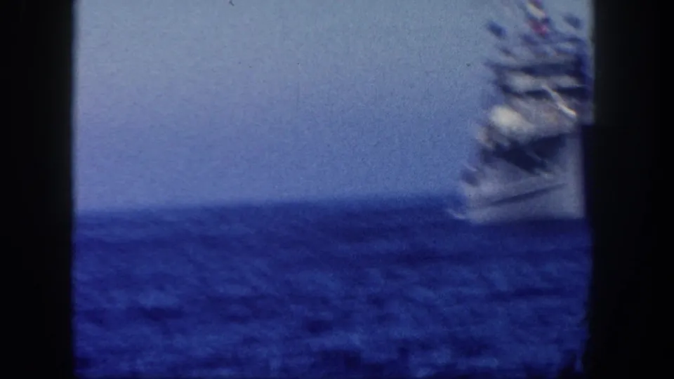 1962 San Diego 8mm frame showing a distant gray naval vessel at sea, partly obscured by dark frame borders.