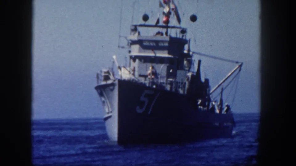 1962 San Diego 8mm view of a gray naval vessel marked 57 sailing across calm blue water.