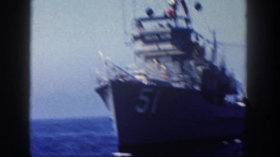 1962 San Diego 8mm frame showing a soft, handheld close pass of naval vessel 57 on open water.