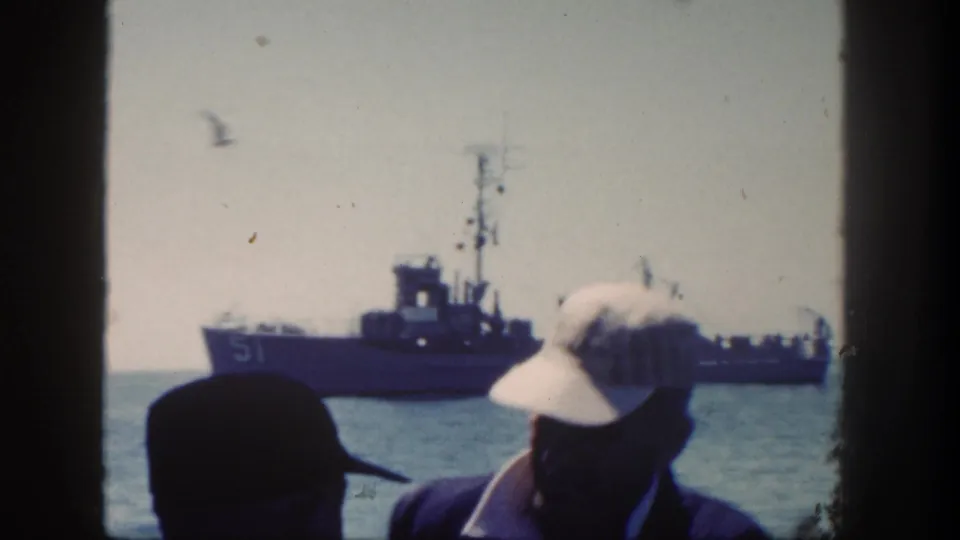 1962 San Diego-area 8mm frame showing sailors in caps near a window or railing with a naval ship marked 51 offshore.