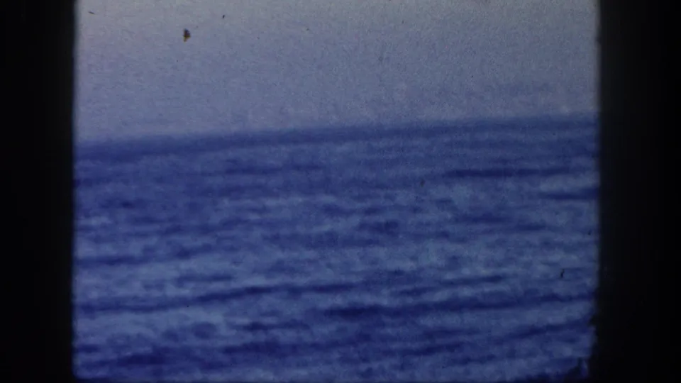 1962 San Diego boat-view frame focused on rough blue ocean water, a hazy horizon, and visible 8mm gate edges.
