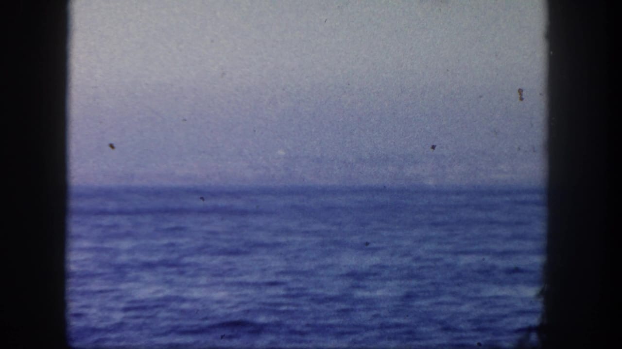 1962 San Diego 8mm frame showing open blue ocean, a low horizon, and soft sky before the sailboat enters view.