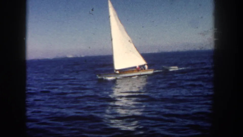A small sailboat continues across blue San Diego waters in a grainy 1962 8mm frame with visible gate borders.