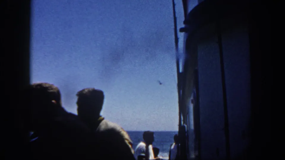 Two adult figures in silhouette near the side of a boat during a 1962 San Diego sea outing, with bright ocean horizon behind them.
