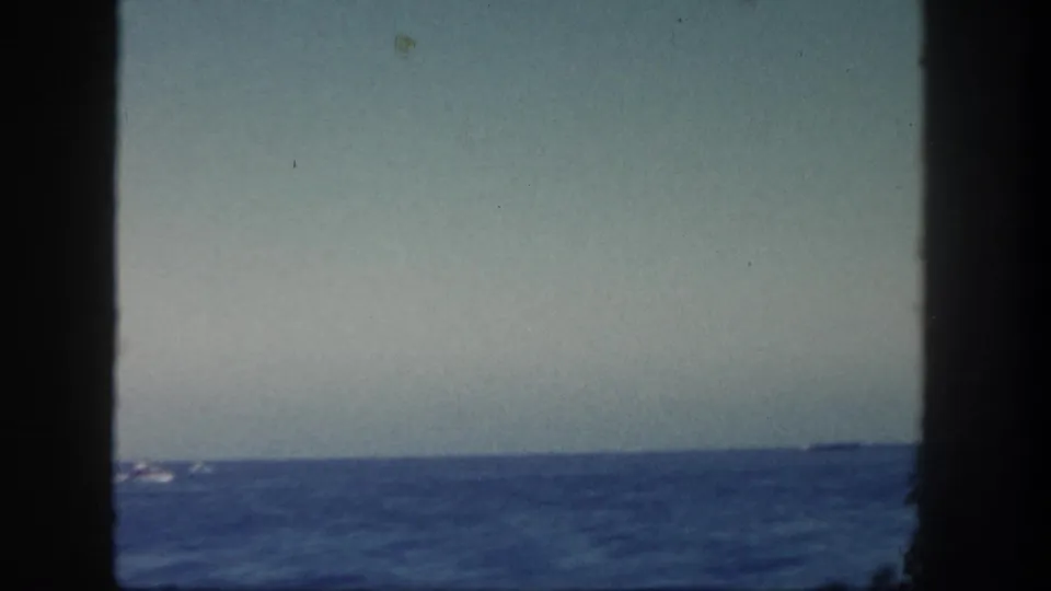 1962 San Diego 8mm ocean view with a low horizon, dark vertical borders, and a faint distant vessel on the water.