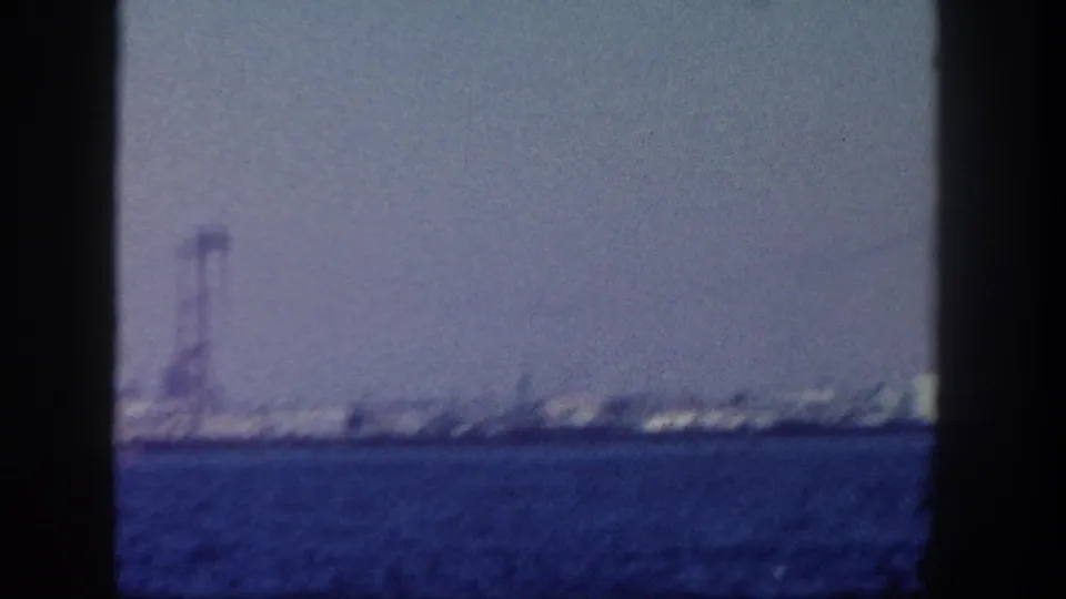 1962 San Diego waterfront view from across choppy water, with a tall tower and hazy shoreline behind dark frame edges.