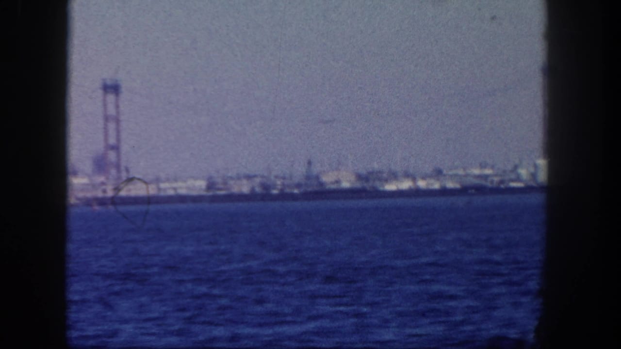 A 1962 San Diego harbor view shows a bridge-like tower and low industrial shoreline beyond open blue water.