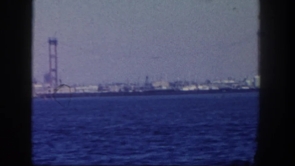 A 1962 San Diego harbor view shows a bridge-like tower and low industrial shoreline beyond open blue water.