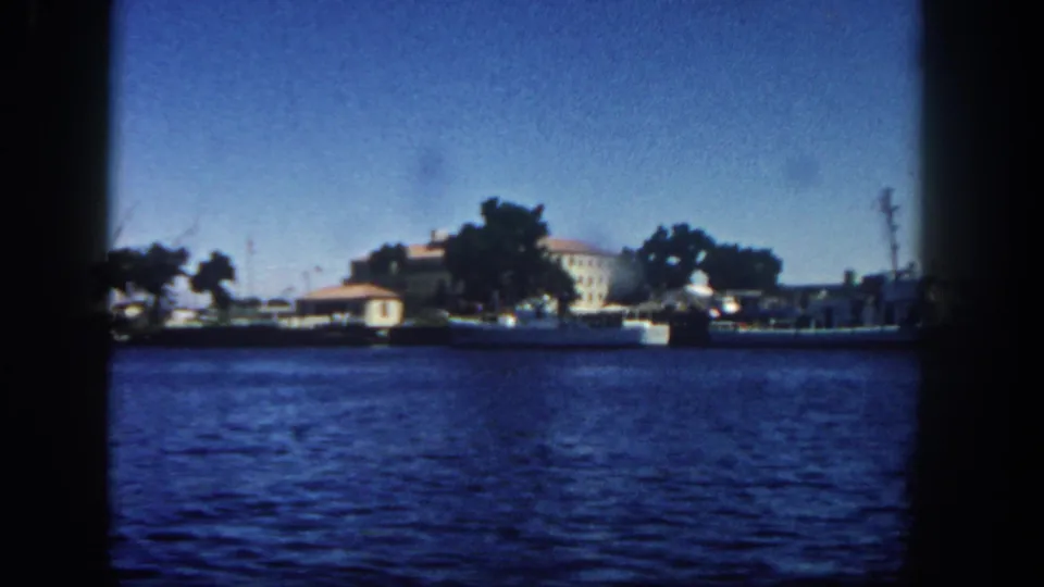 Final 1962 San Diego waterfront frame showing boats, trees, low buildings, and a utility pole across the harbor.