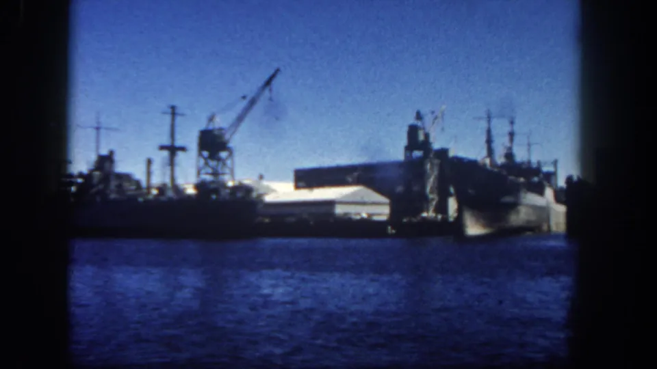 Blue 8mm harbor scene in San Diego, 1962, with docked ships, industrial cranes, and waterfront structures in the distance.