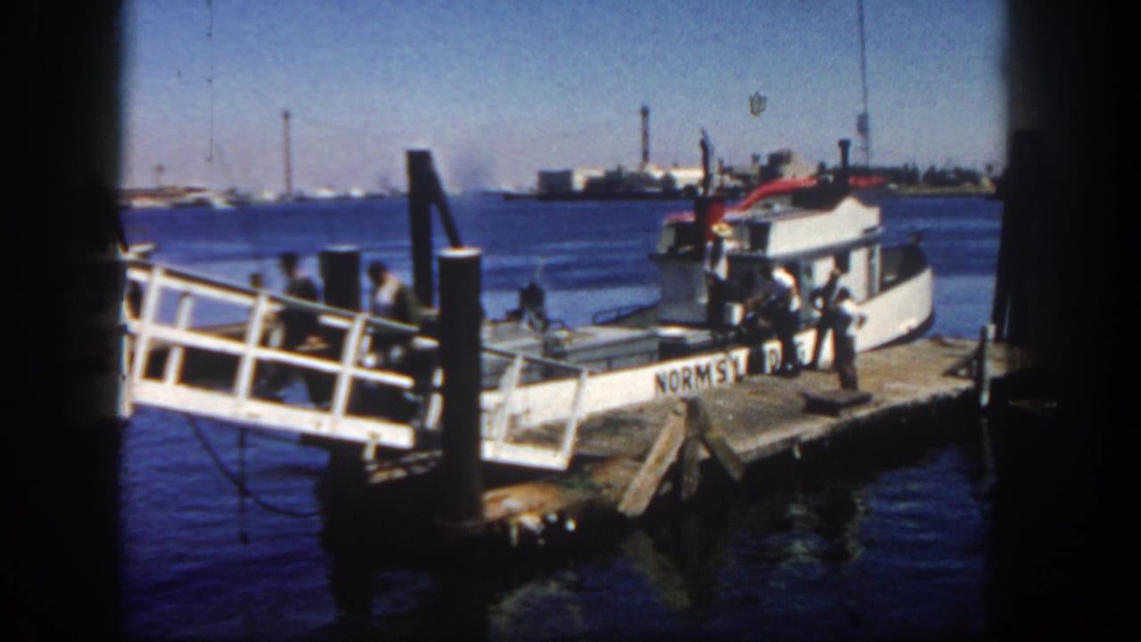 Boat moored at the pier with men standing beside the ramp and water behind.