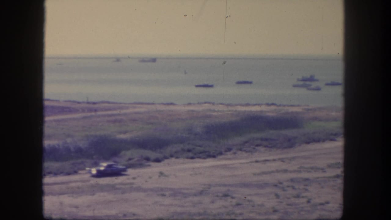 San Pedro, California, 1962 frame with a vehicle near the lower road and several large ships offshore in hazy daylight.