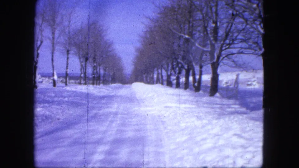 8mm winter frame from Proctor, Minnesota in 1963 showing a snowy roadside path, bare trees, and tracked snow.