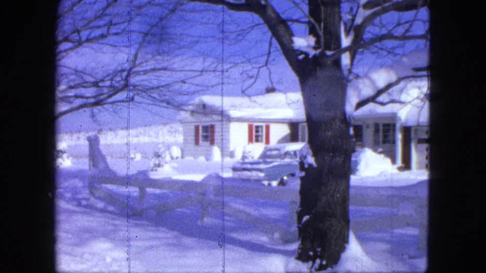 Snowy Proctor residential exterior with a low house, bare winter tree, white fence, and car in the driveway.