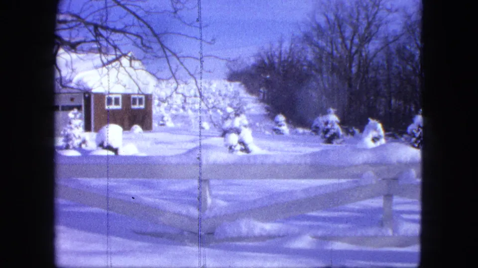 End frame of the 1963 Proctor winter exterior, with the house partly cropped and the snowy fence and trees prominent.