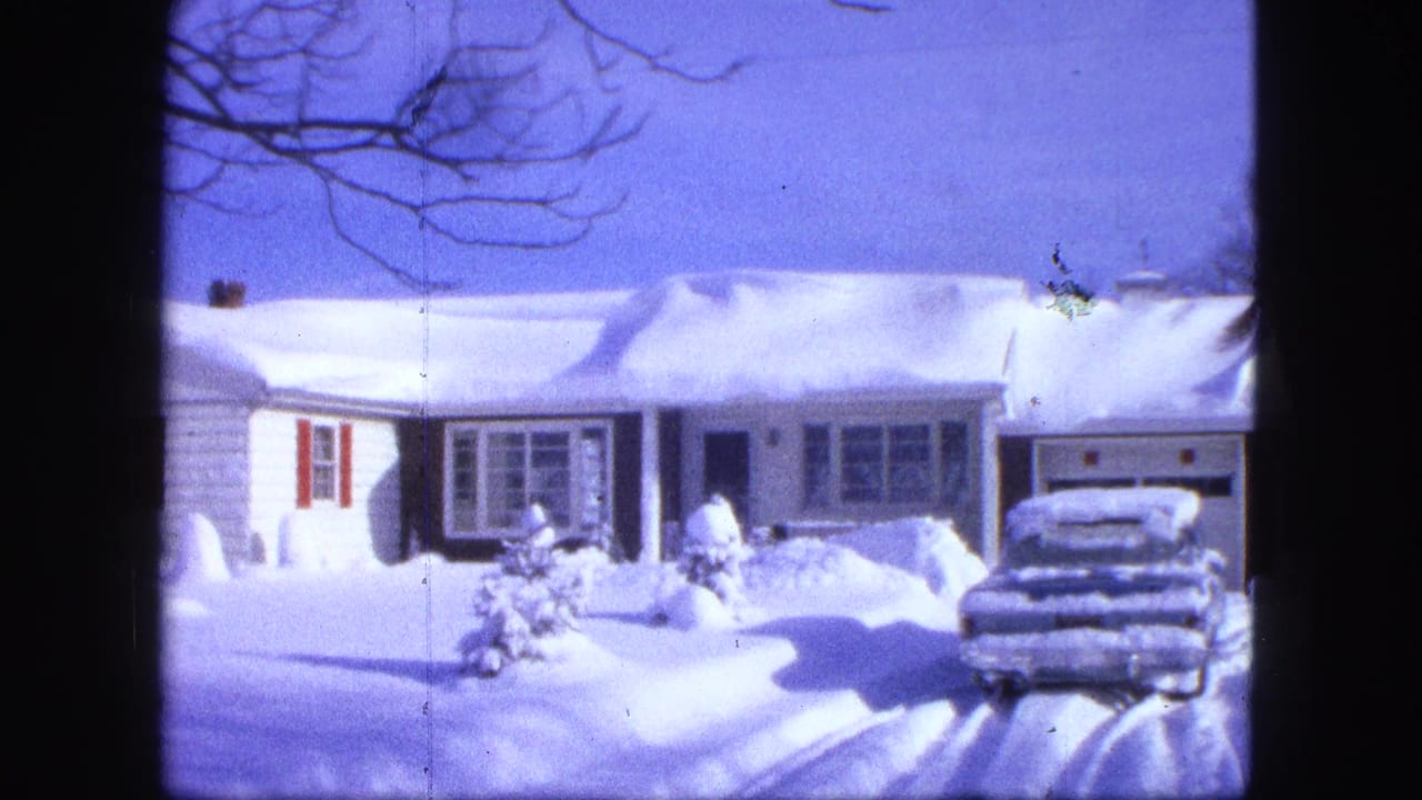 1963 Proctor, Minnesota 8mm frame showing a white ranch-style house under deep snow, with red shutters and a snow-covered driveway car.