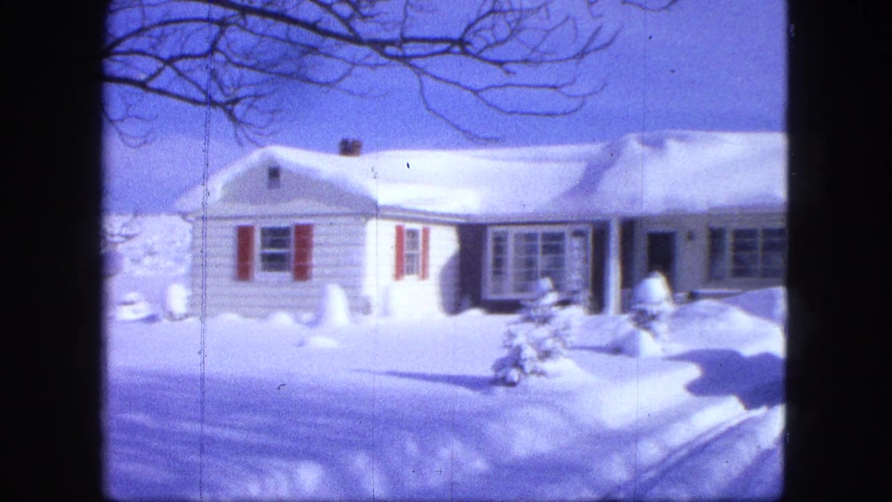 Snow-covered white suburban house with red shutters and deep snow across the yard.