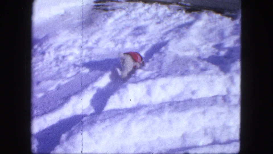 Small red-coated dog works through deep snow in a residential winter scene in Proctor, Minnesota.