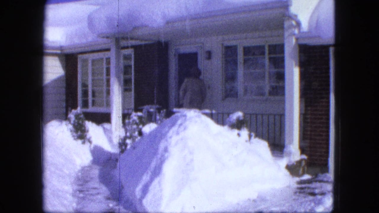 A bundled person reaches the front doorway of a Proctor, Minnesota house in 1963, with snowbanks piled around the porch and walkway.