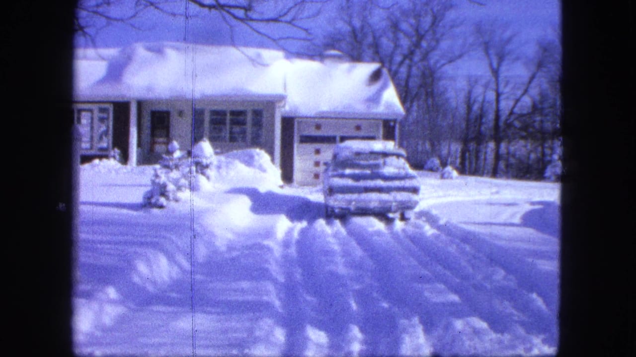 1963 8mm home-movie view in Proctor, Minnesota, showing a snow-covered suburban house and car in the driveway.