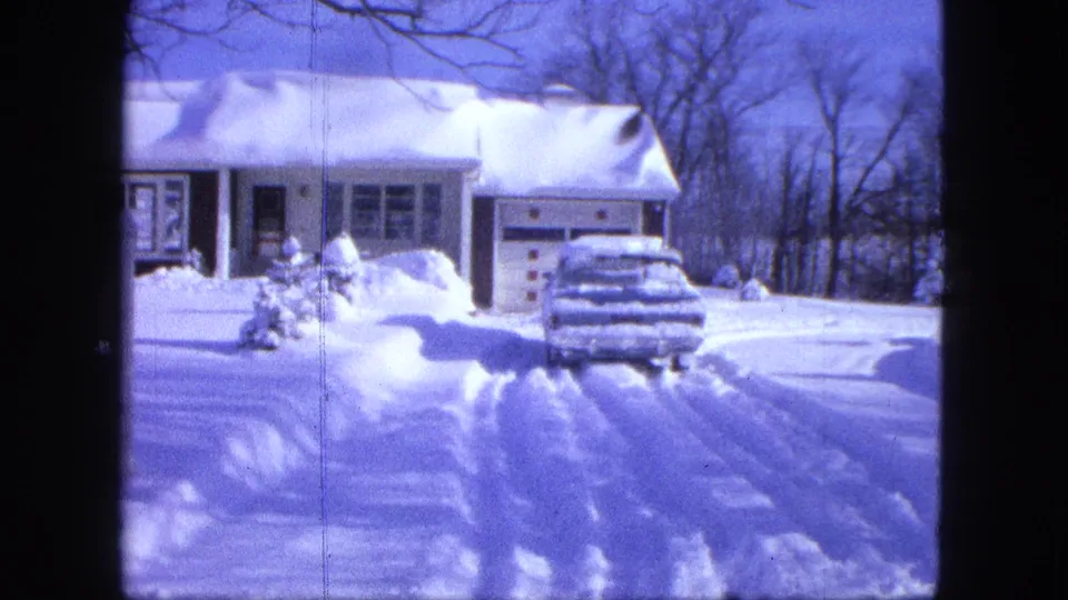 1963 8mm home-movie view in Proctor, Minnesota, showing a snow-covered suburban house and car in the driveway.