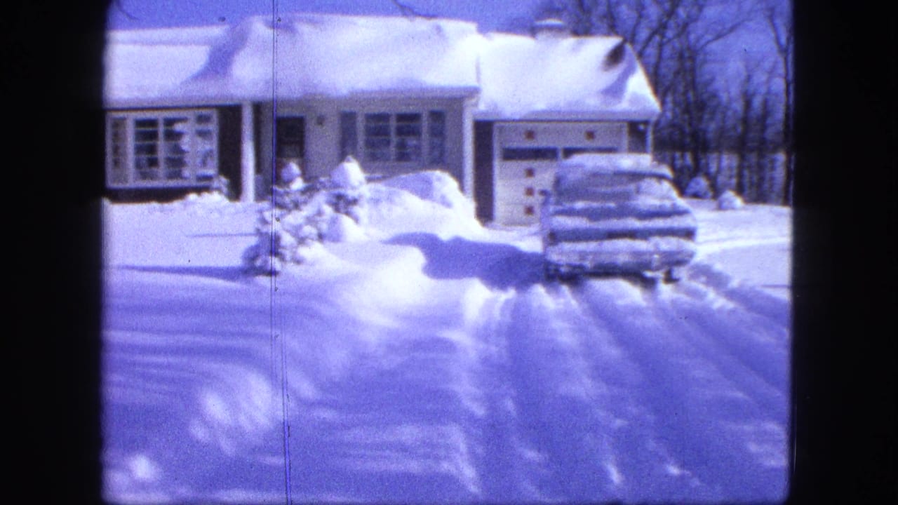 Snowy driveway and house with a snow-covered car near the garage.