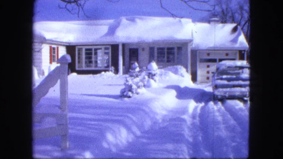 Snowdrifts fill the yard in front of the Proctor house, with a partial white fence visible near the foreground.