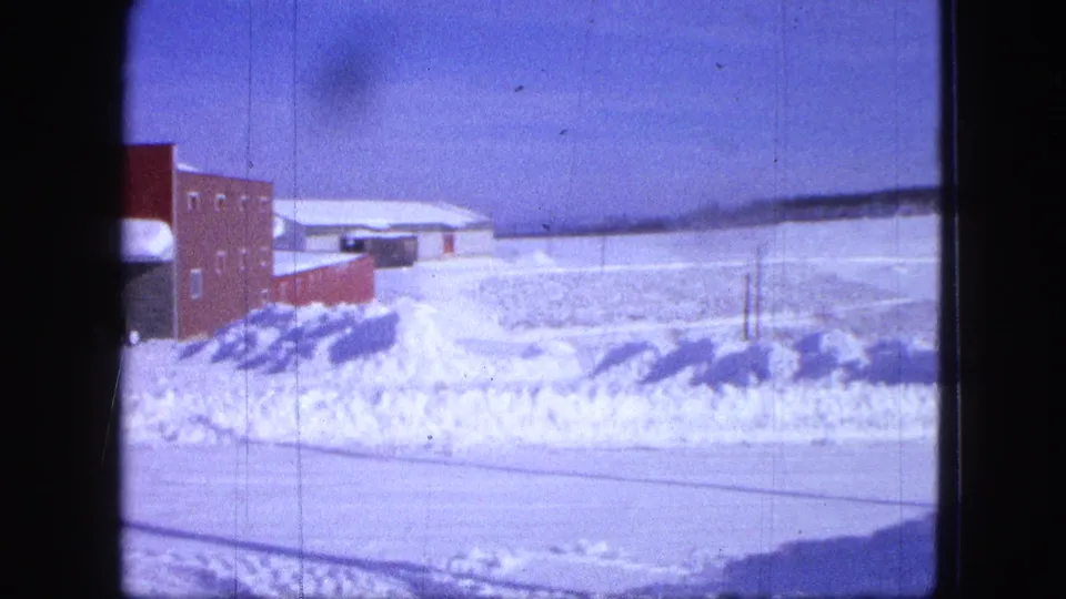 1963 Proctor, Minnesota frame showing the brick building again at the edge of a snowy field with utility poles nearby.