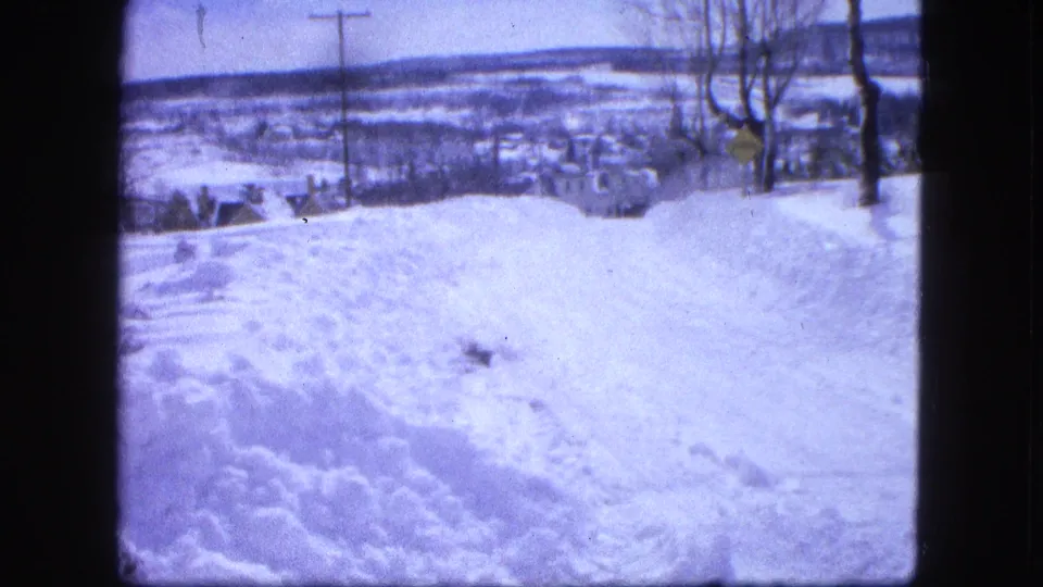 Snowy Proctor, Minnesota overlook with a plowed road, bare trees, utility pole, and distant town landscape.