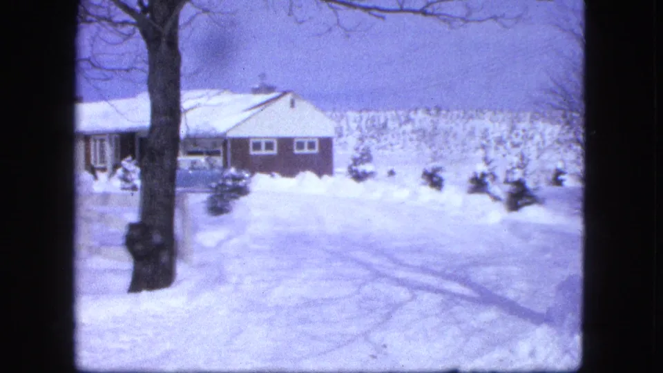 1963 Proctor, Minnesota frame with a house partly framed by a bare tree and deep snow across the yard.