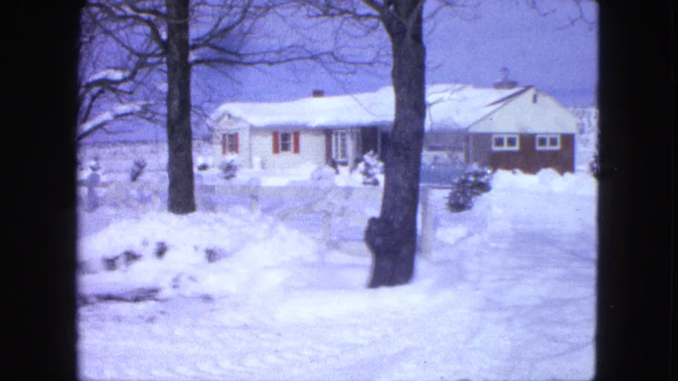1963 Proctor, Minnesota frame showing the snowy residential scene widened to include two bare trees and the house.